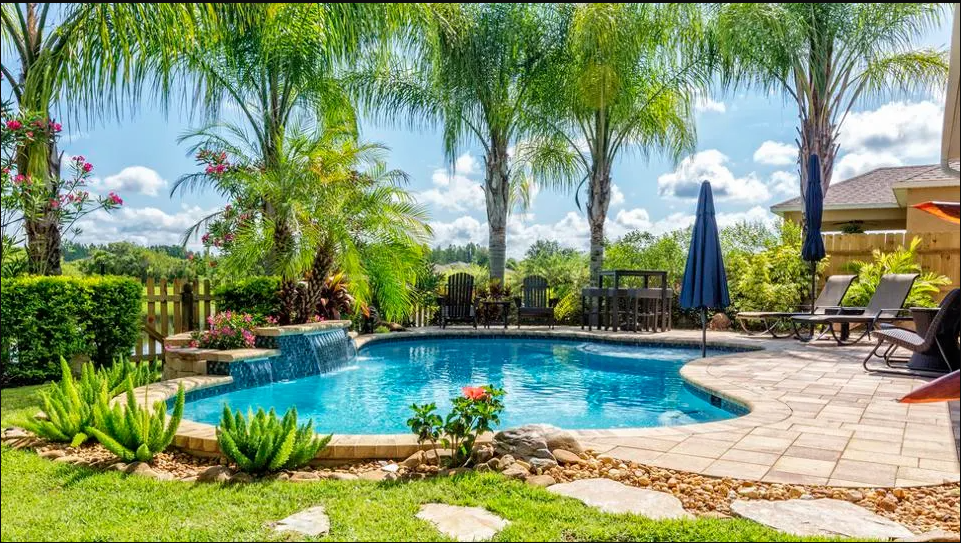 A serene backyard featuring a sparkling pool surrounded by stylish patio furniture for relaxation and leisure.